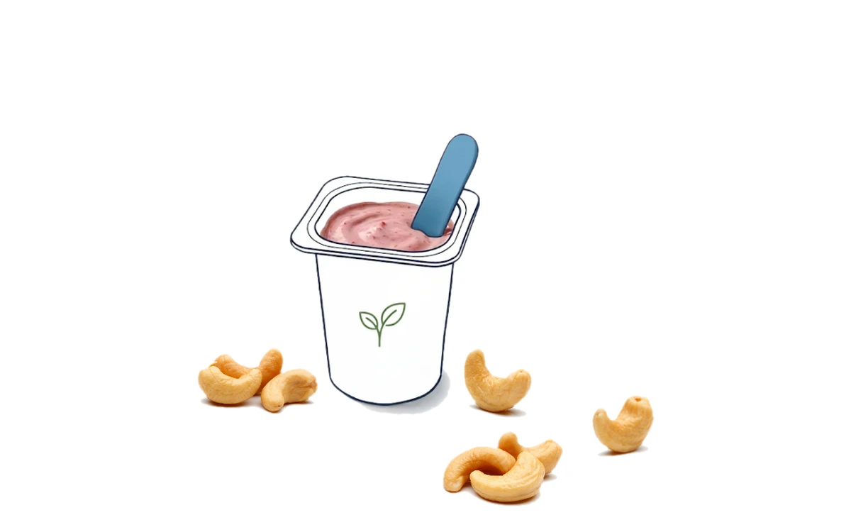 An illustrated cup of cashew-based plant-based yogurt with a pink spoon, a green leaf logo, and whole cashews scattered around the base on a cream background.